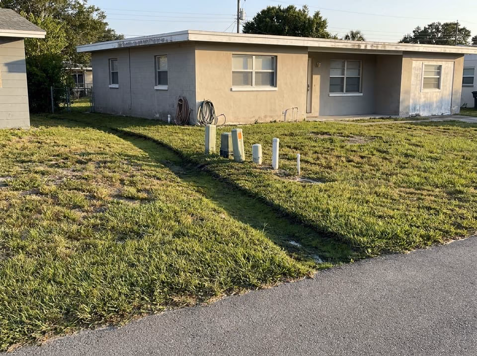 Sunken strip of greener St. Augustine grass over a leaking sewer line in a Florida front yard
